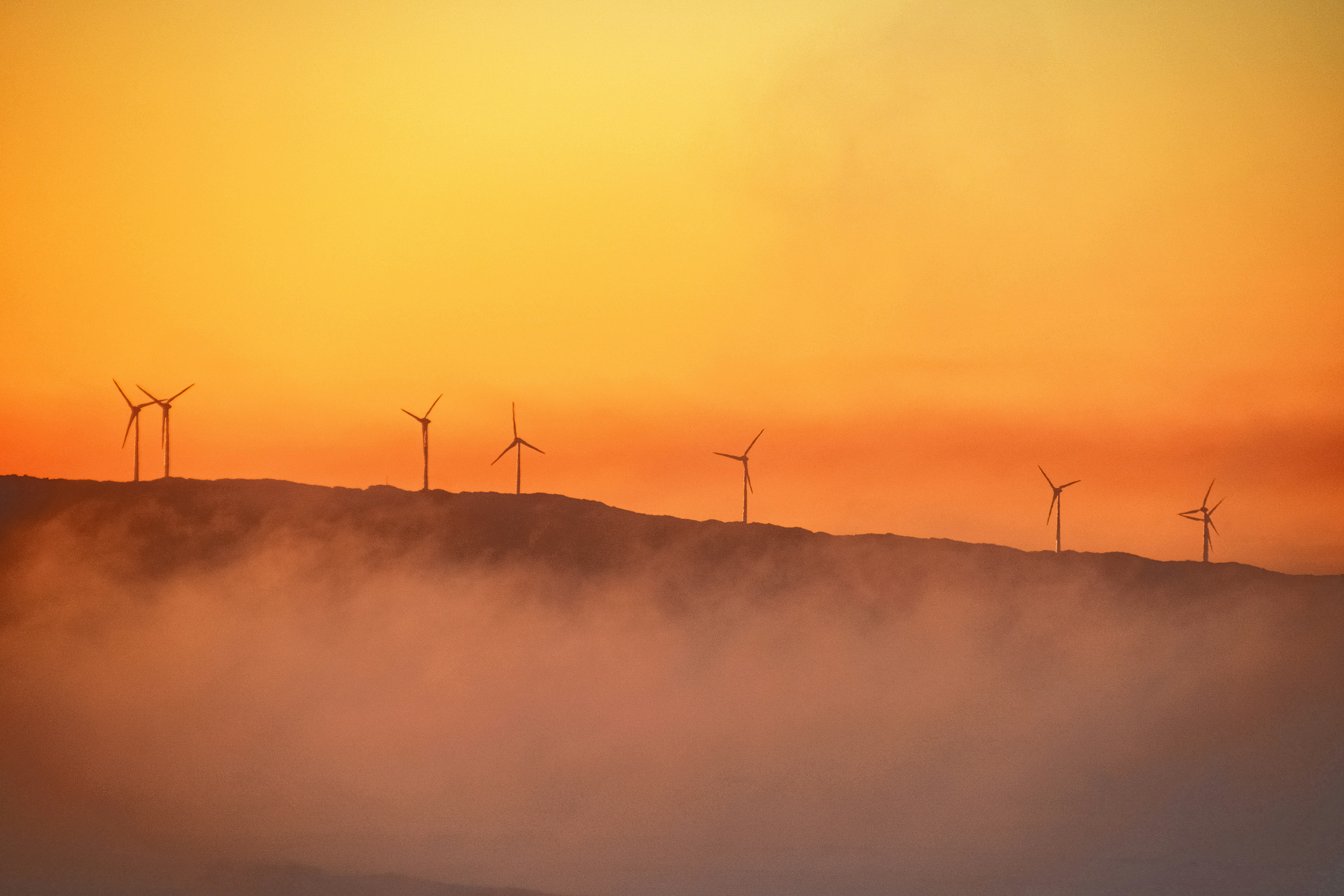 3 wind turbines on foggy mountain